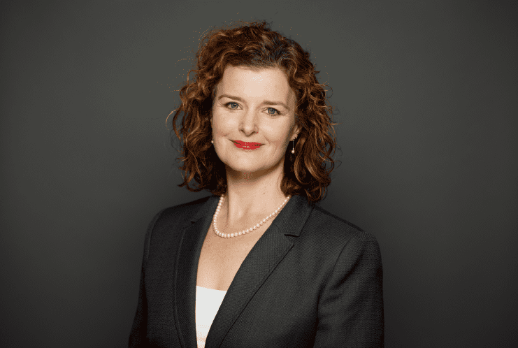 Woman in business attire, smiling confidently.