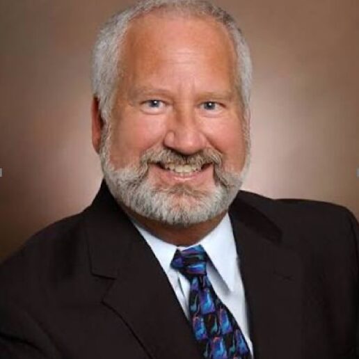 Man in suit smiling with a beard.