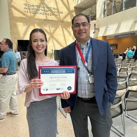 Woman holding award certificate standing with colleague