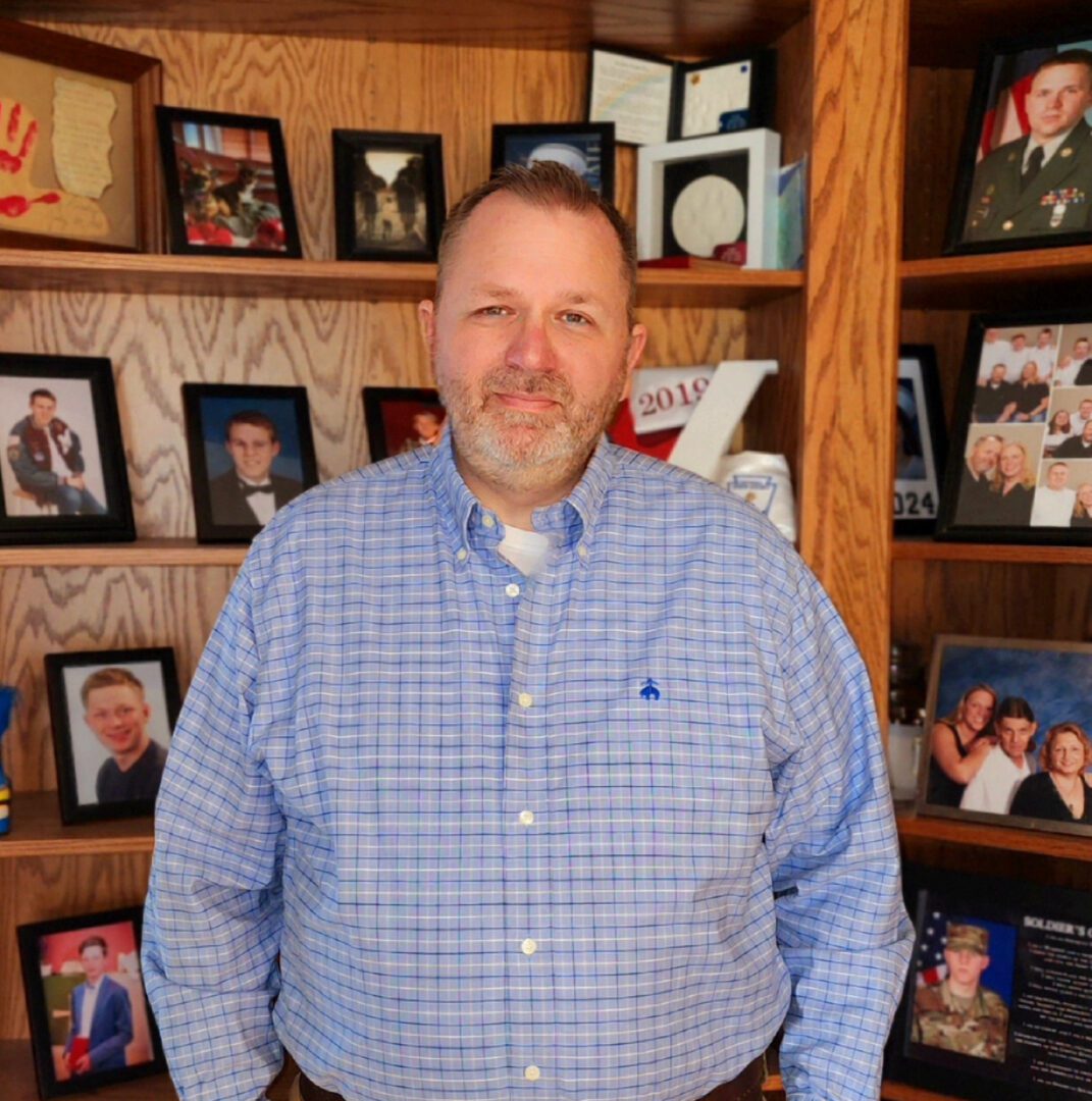 Man in blue shirt in front of photos