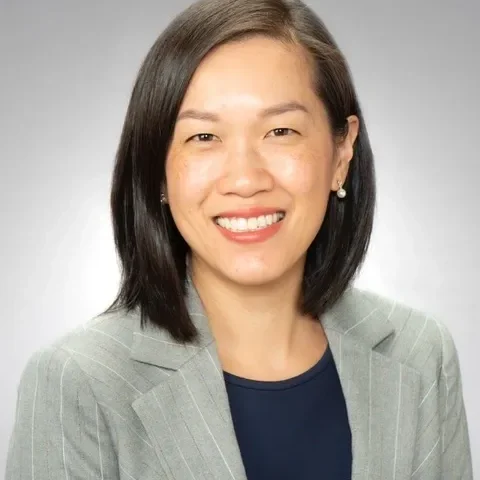 Smiling person in a gray suit jacket.