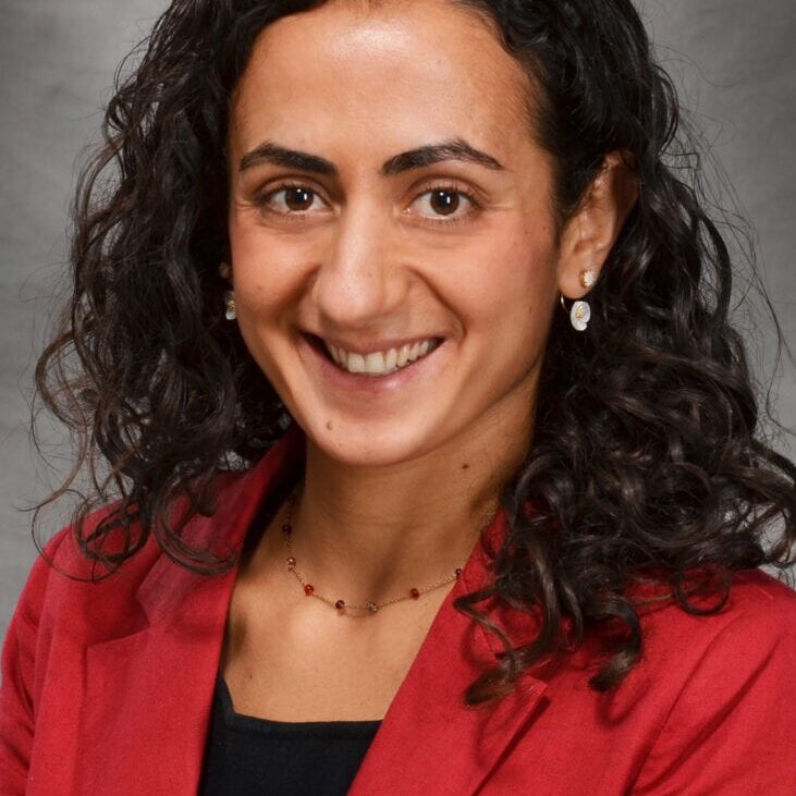 Smiling woman with curly hair in red blazer