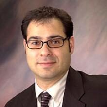 Headshot of person in suit and glasses