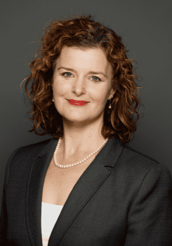 Woman in business attire, smiling confidently.