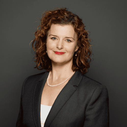 Woman in business attire, smiling confidently.