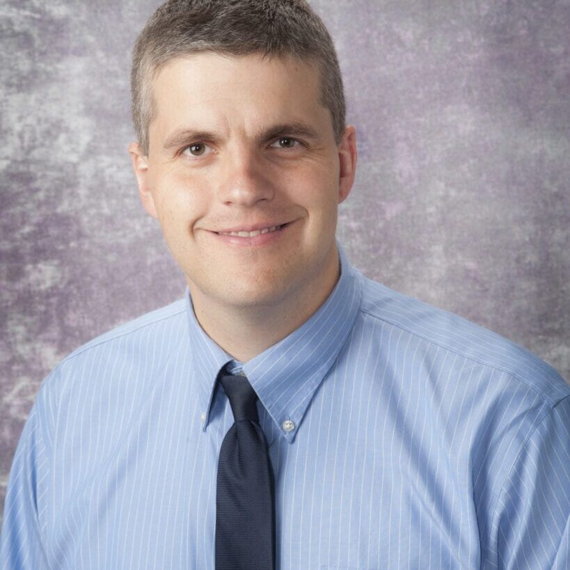Smiling man in blue shirt and tie