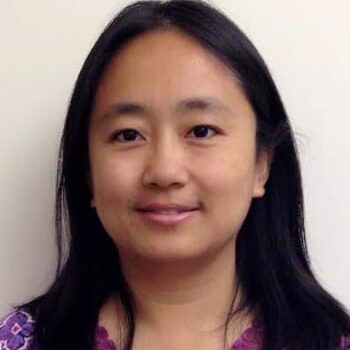 Smiling person with black hair, purple blouse