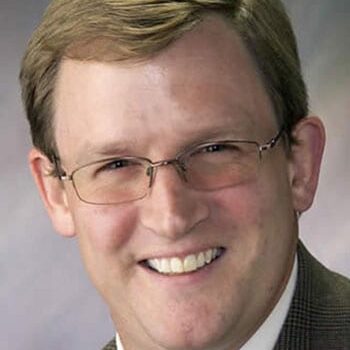 Smiling bespectacled man in suit jacket